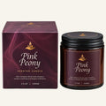 Pink Peony scented candle in a dark amber glass jar with a black lid, shown next to its matching dark purple box packaging on a white background.