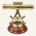 A brass marine surveyor's transit and compass set on a polished dark wood base, photographed against a solid white background.